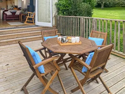 a wooden table and chairs on a deck at Swallows in Porthscatho