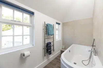 a white bathroom with a tub and a window at Mariners Cottage in Saint Mawes