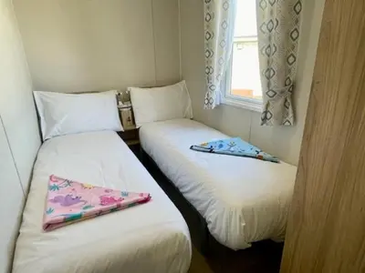 two twin beds in a room with a window at Polperro Seaside Retreat in Polperro