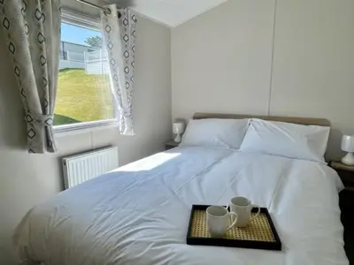 a tray with two cups on a bed with a window at Polperro Seaview Retreat in Polperro