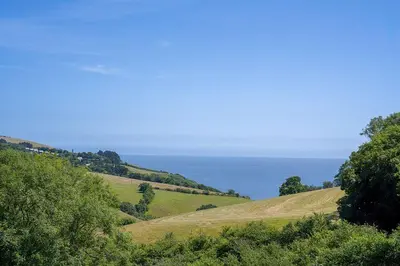 a grassy hill with the ocean in the background at Polperro Seaview Retreat in Polperro
