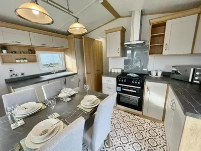 a kitchen with a dining table with chairs and a counter at Polperro Seaview Lodge in Polperro