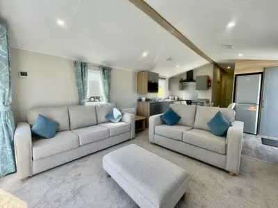 a living room with two couches and a kitchen at Polperro Seaview Lodge in Polperro