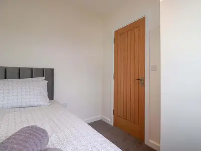 a bedroom with a bed and a wooden door at Yonja Homes in St Austell