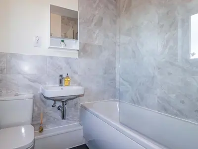a bathroom with a sink and a toilet and a bath tub at Yonja Homes in St Austell