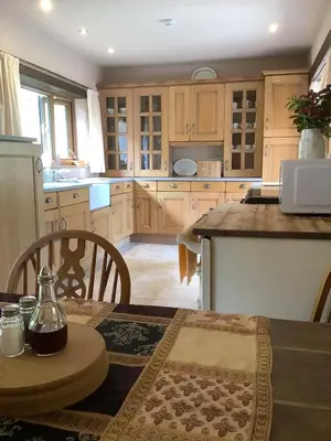 a kitchen with wooden cabinets and a wooden table at Poldurn in St Austell
