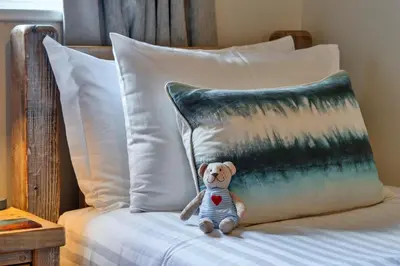 a teddy bear sitting on a bed with a pillow at Finest Retreats - Gwelmor in Widemouth Bay