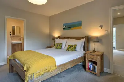 a bedroom with a large bed with a yellow blanket at Finest Retreats - Gwelmor in Widemouth Bay