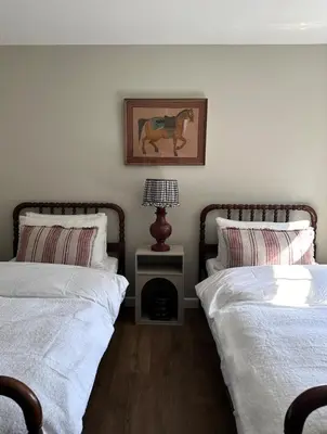 a bedroom with two beds and a lamp on a night stand at The Old Piggery, countryside barn with hot tub in Leedstown