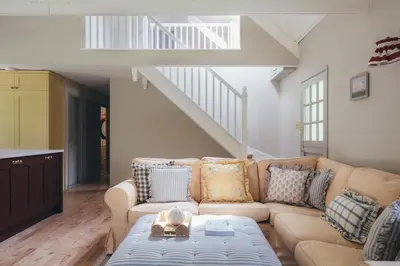 a living room with a couch and a staircase at The Old Piggery, countryside barn with hot tub in Leedstown