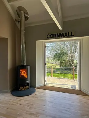 a fireplace in a room with a window and a gate at The Old Piggery, countryside barn with hot tub in Leedstown