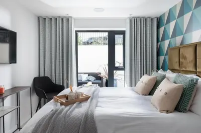 a bedroom with a large white bed and a chair at Fistral house Beachfront Bliss in Crantock