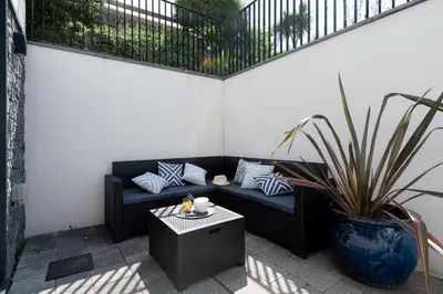 a patio with a black couch and a table at Fistral house Beachfront Bliss in Crantock