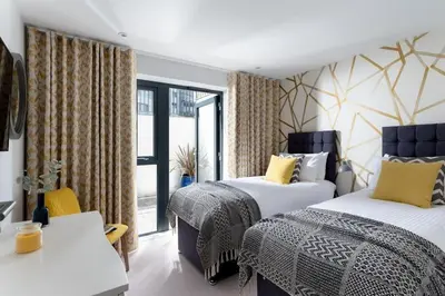 a hotel room with two beds and a balcony at Fistral house Beachfront Bliss in Crantock