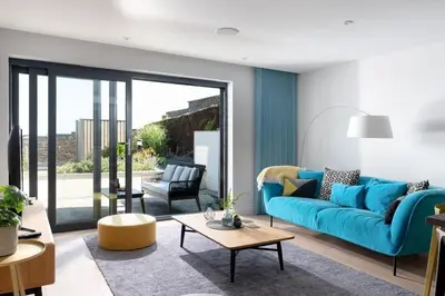 a living room with a blue couch and a table at Fistral house Beachfront Bliss in Crantock