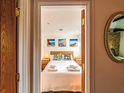 a bedroom with a white bed and a mirror at Holiday Home Shanty Cottage by Interhome in Mevagissey
