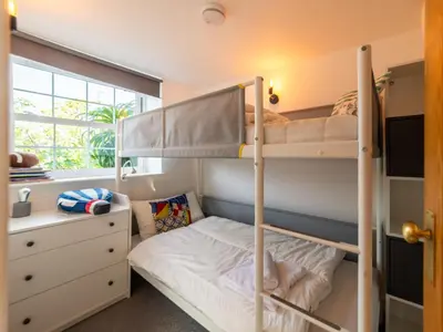 a bedroom with two bunk beds and a desk at Holiday Home Shanty Cottage by Interhome in Mevagissey