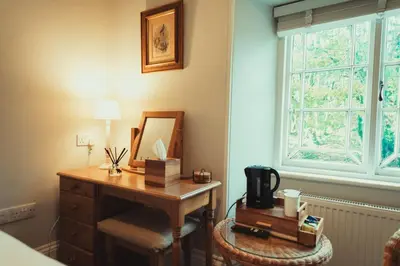 a room with a desk with a mirror and a window at The Falcon Inn in Saint Mawgan