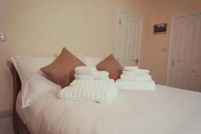 a pile of white towels stacked on a bed at The Falcon Inn in Saint Mawgan