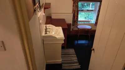 a bathroom with a sink and a kitchen with a table at Plenteth in Truro