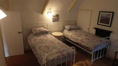 a bedroom with two beds and a table in it at Plenteth in Truro