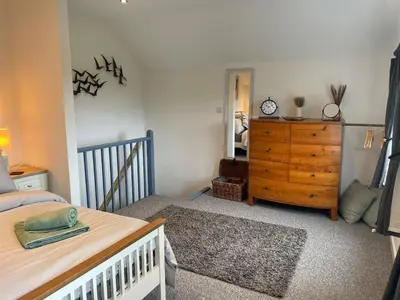 a bedroom with a bed and a wooden dresser at Hideaway Cottage in Polperro