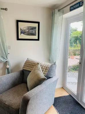 a couch in a living room with a sliding glass door at Hideaway Cottage in Polperro