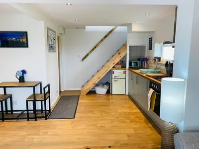 a kitchen with a staircase leading up to a loft at Hideaway Cottage in Polperro