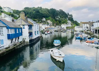 a small boat is docked in a river with houses at Hideaway Cottage in Polperro