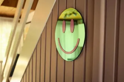 a green smiley face sign on a wall at Little Pol in Saint Columb Road Station