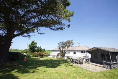 a house with a table and chairs in the yard at Little Penrose Cottage in Bude