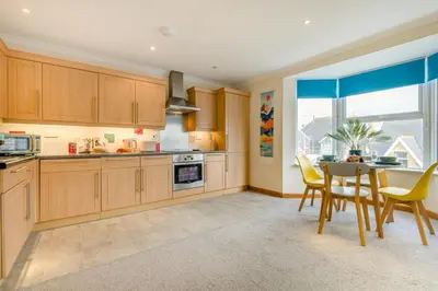 a kitchen with wooden cabinets and a table with chairs at 1 Bed in Newquay oc-o33805 in Newquay