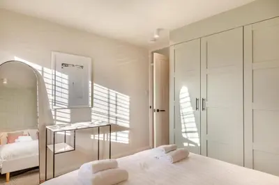 a white bedroom with a bed and a mirror at 2 Bed in Trevarrian oc-c33855 in Mawgan Porth