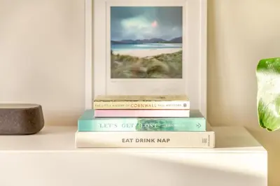 a stack of books sitting on a shelf with a picture at 2 Bed in Trevarrian oc-c33855 in Mawgan Porth