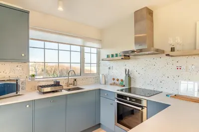 a kitchen with blue cabinets and a large window at 2 Bed in Trevarrian oc-c33855 in Mawgan Porth