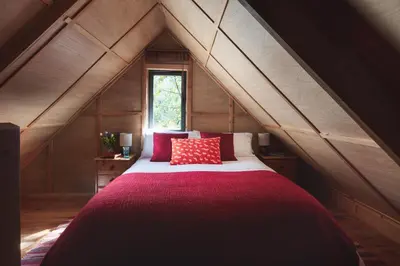 a bedroom with a large bed in an attic at The Beech Hut, Wood Fired Hot Tub, St Kew Escapes in Saint Kew
