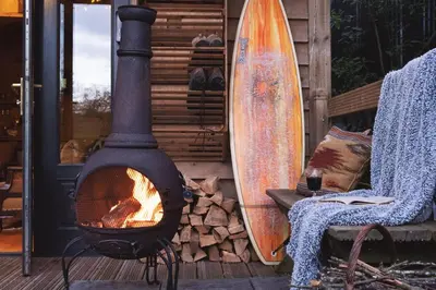 a wood fired oven sitting next to a surfboard at The Beech Hut, Wood Fired Hot Tub, St Kew Escapes in Saint Kew