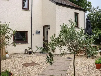 a house with a garden with trees in front of it at Camellia Cottage in Bodmin