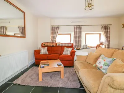 a living room with a couch and a table at Camellia Cottage in Bodmin
