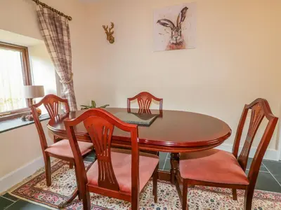 a dining room with a wooden table and chairs at Camellia Cottage in Bodmin