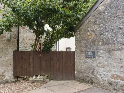 a wooden gate with a sign on the side of a building at Camellia Cottage in Bodmin