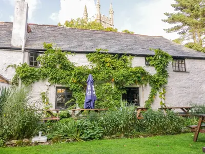 an old white building with a blue umbrella in front of it at Camellia Cottage in Bodmin