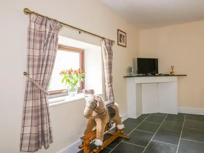 a room with a rocking horse in front of a window at Camellia Cottage in Bodmin