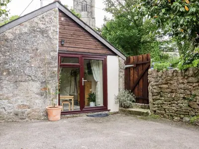 a small stone building with a window and a fence at Lannlyvri Lodge in Bodmin