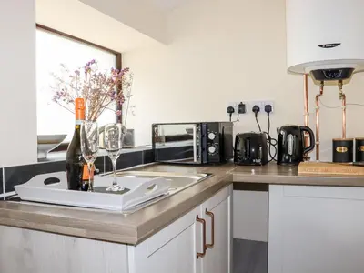 a kitchen counter with a sink and a bottle of wine at Lannlyvri Lodge in Bodmin