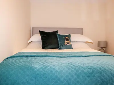 a bed with two pillows with a dog on it at Lannlyvri Lodge in Bodmin