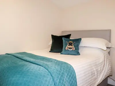 a bed with a pillow with a dog on it at Lannlyvri Lodge in Bodmin
