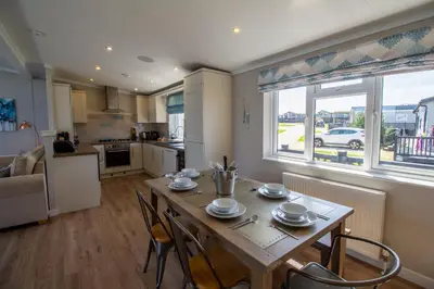 a kitchen and living room with a table and chairs at Teal Lodge Cornwall - hot tub, indoor pool, near Perranporth in Cubert