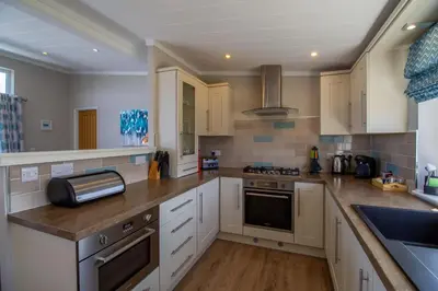 a kitchen with white cabinets and a counter top at Teal Lodge Cornwall - hot tub, indoor pool, near Perranporth in Cubert