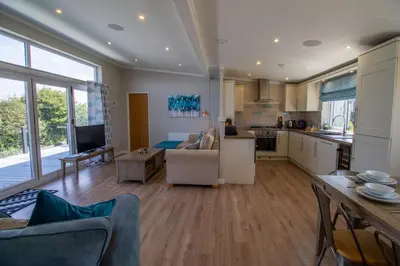 a kitchen and living room with a couch and a table at Teal Lodge Cornwall - hot tub, indoor pool, near Perranporth in Cubert